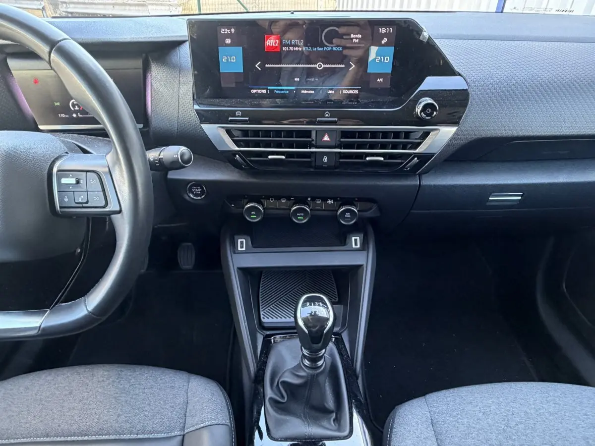Vue intérieure centrée sur la console et le volant cuir noir de la Citroën C4 PureTech 130 S&S Shine 2022.
