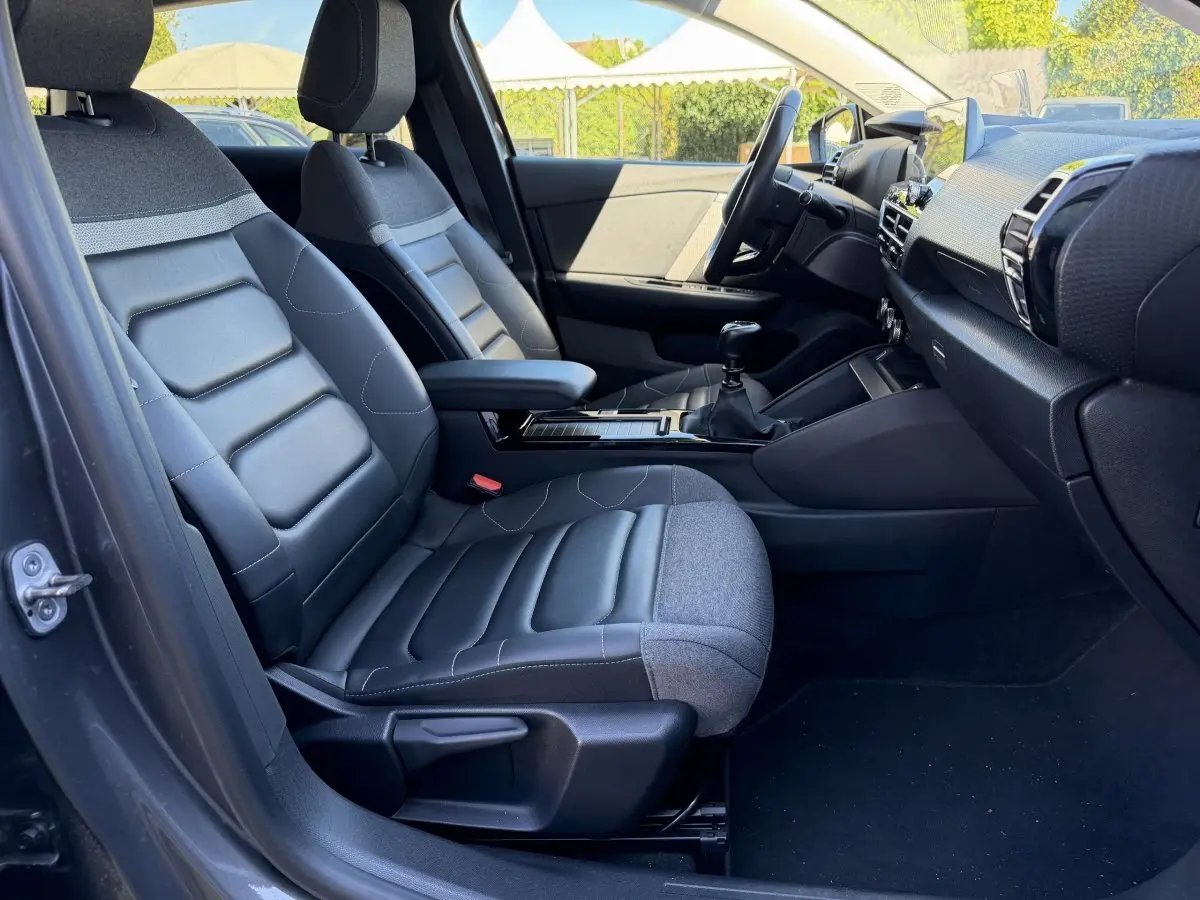 Vue intérieure côté conducteur de la Citroën C4 gris foncé, sièges bi-matière cuir et tissu, tableau de bord moderne.