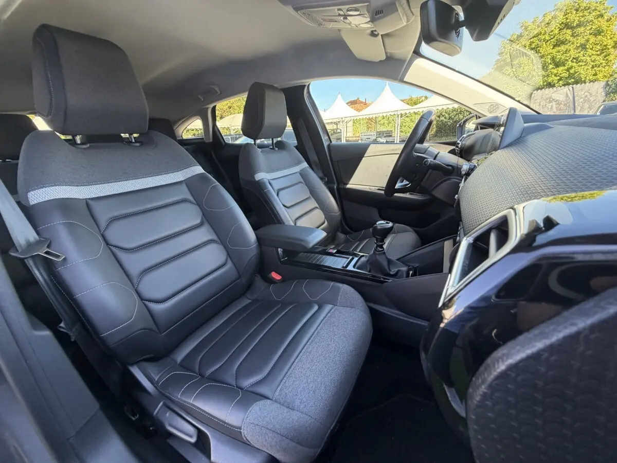 Vue intérieure côté conducteur de la Citroën C4 2022, sièges bi-matière gris et tableau de bord moderne.