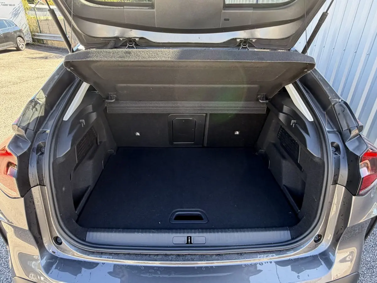 Coffre ouvert vu de l'arrière d'une Citroën C4 PureTech 130 S&S Shine gris foncé, espace de chargement vide.