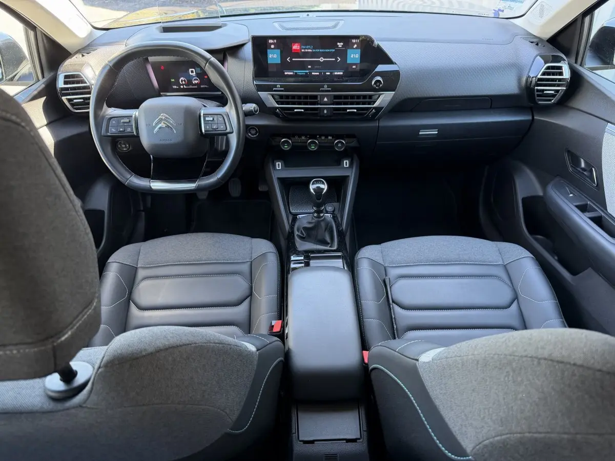 Vue intérieure avant de la Citroën C4 PureTech 130 S&S Shine 2022, tableau de bord moderne avec écran tactile et volant cuir.