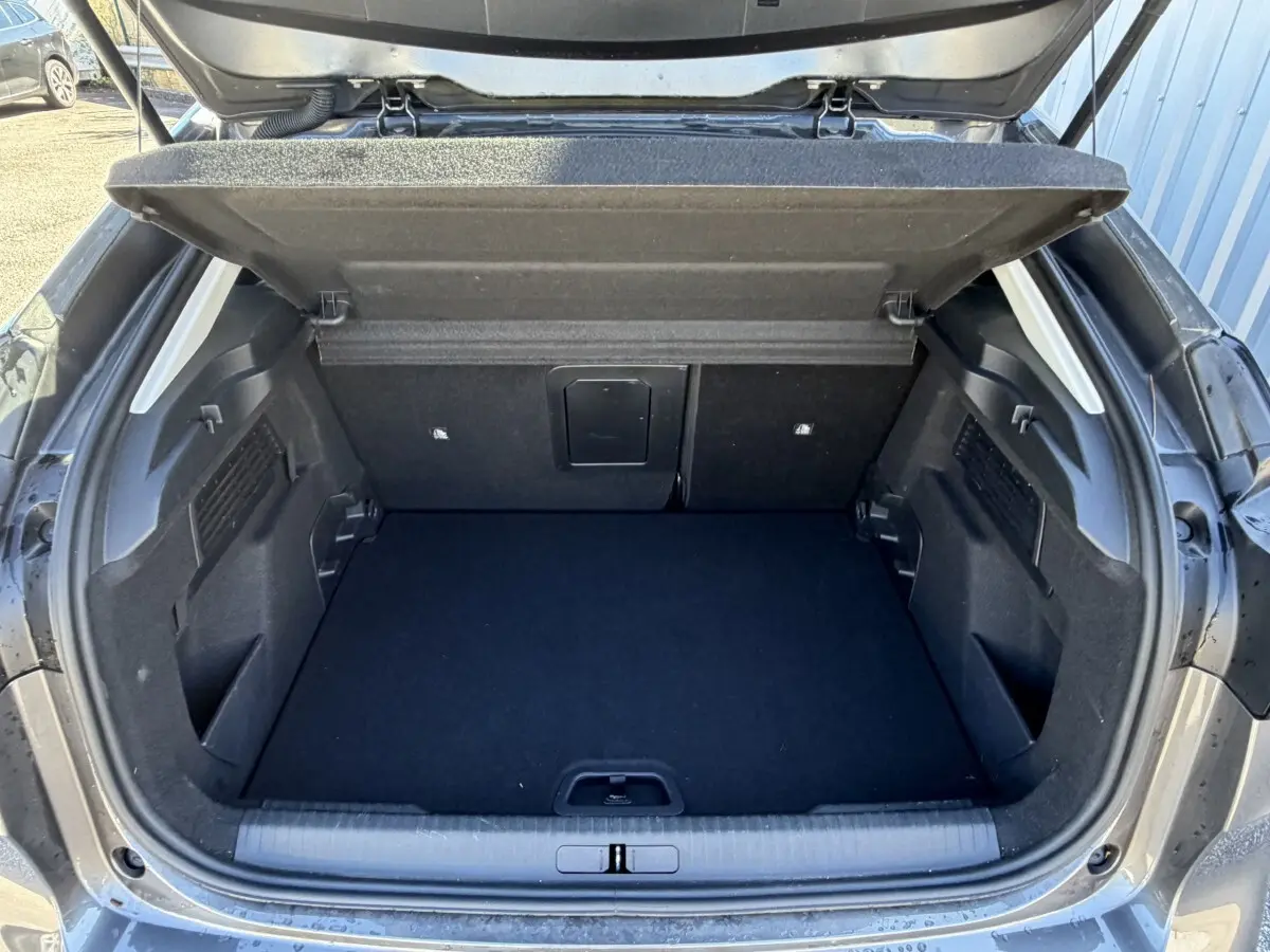 Coffre ouvert vu de l'arrière d'une Citroën C4 gris foncé, montrant un espace de chargement propre et spacieux.