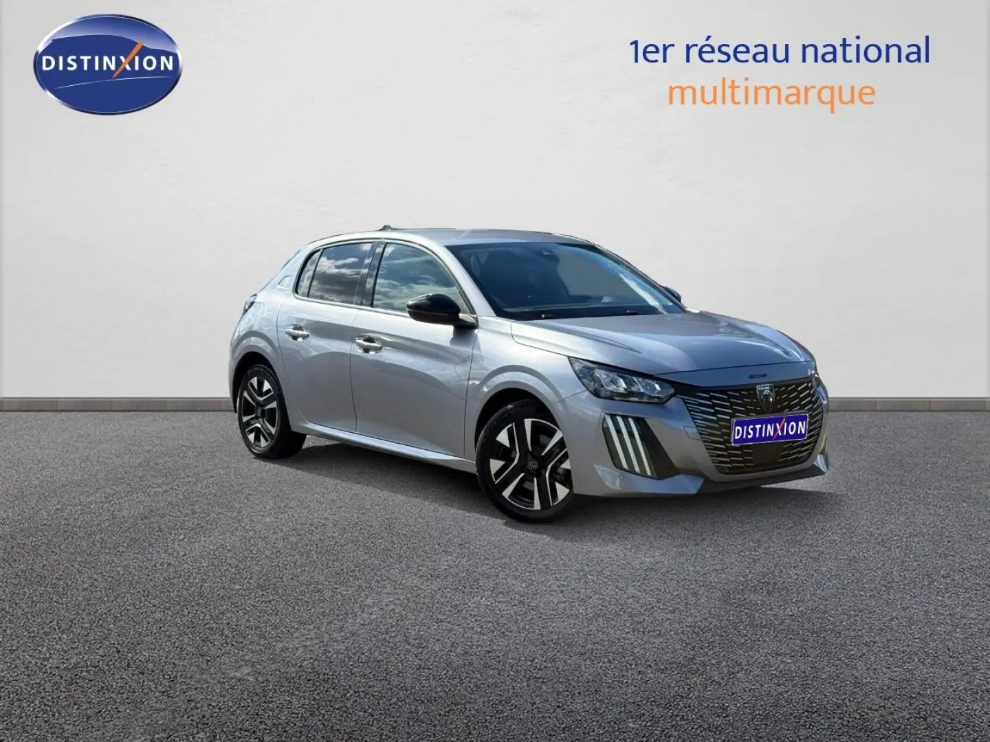 Peugeot 208 gris Artense vue 3/4 avant droit, avec calandre noire distinctive et jantes alliage bicolores.