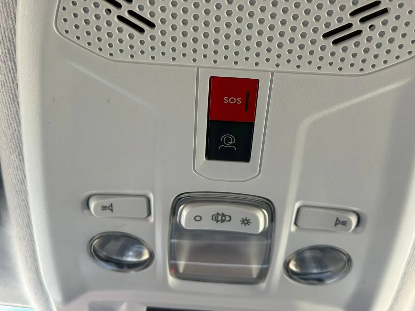 Gros plan sur la console de plafonnier intérieur gris clair avec bouton SOS et commandes d’éclairage de la Peugeot 208 2025.