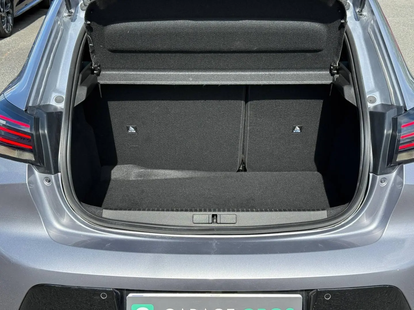 Coffre ouvert vu de l'arrière d'une Peugeot 208 gris Artense avec feux arrière LED visibles.
