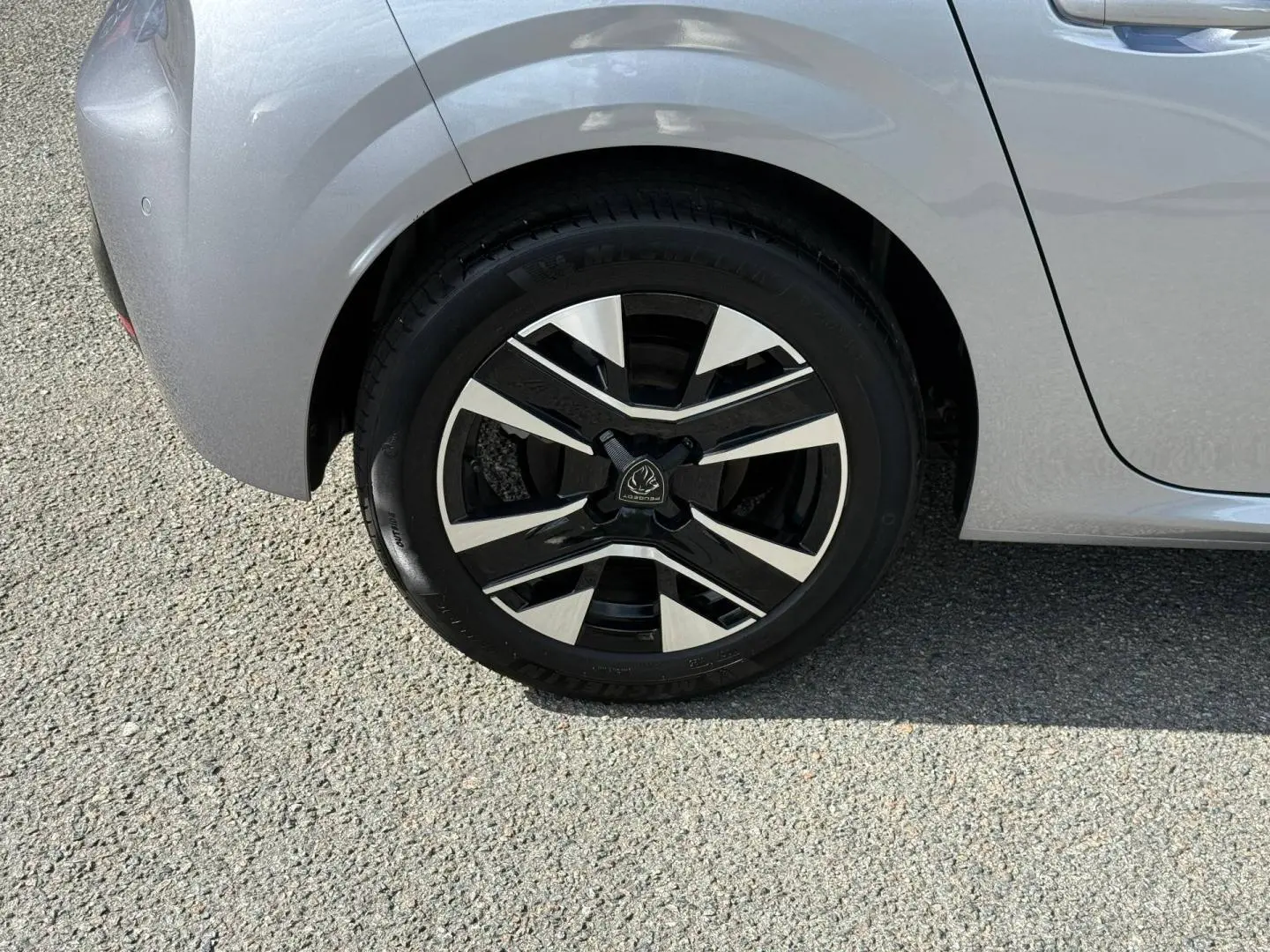 Gros plan sur la roue arrière droite de la Peugeot 208 gris Artense avec jante alu au design moderne.