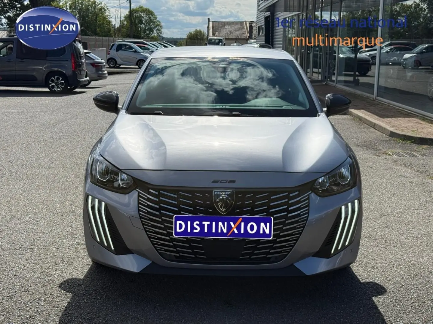 Vue avant d'une Peugeot 208 gris Artense avec feux diurnes LED en forme de griffes et calandre noire distinctive.
