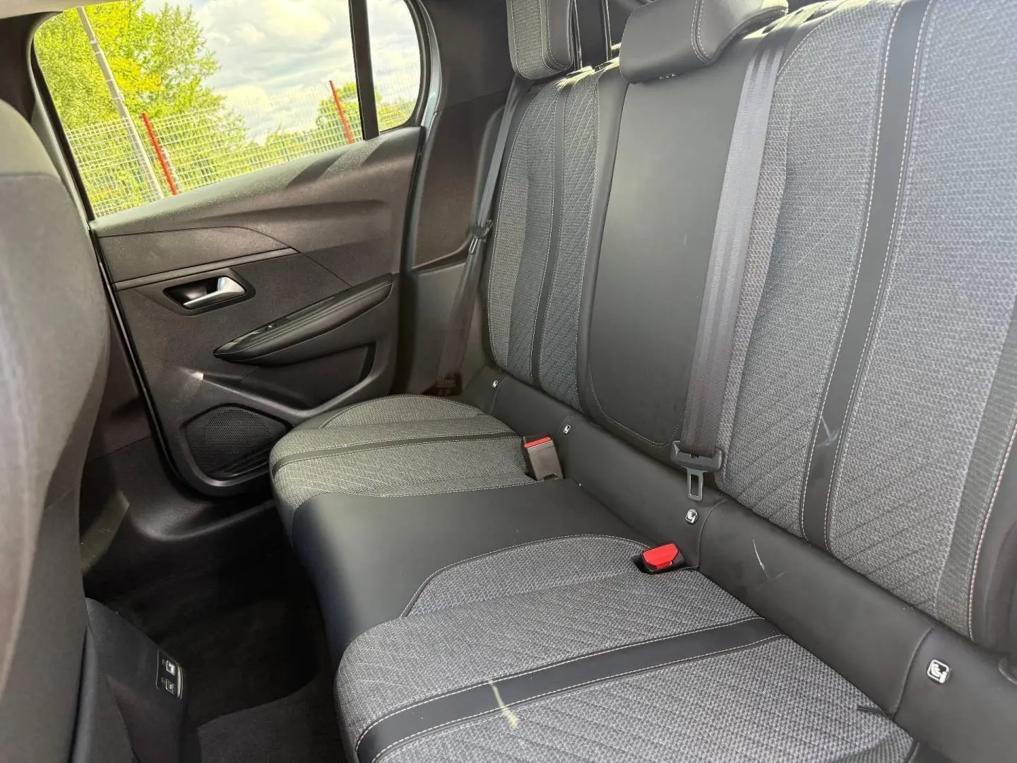 Vue intérieure côté gauche sur la banquette arrière tissu gris et cuir noir de la Peugeot 208 1.2 100ch Allure 2025.