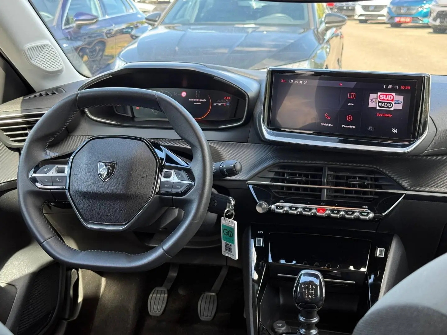 Vue intérieure du tableau de bord et volant de la Peugeot 208 gris Artense avec écran tactile et boîte manuelle.