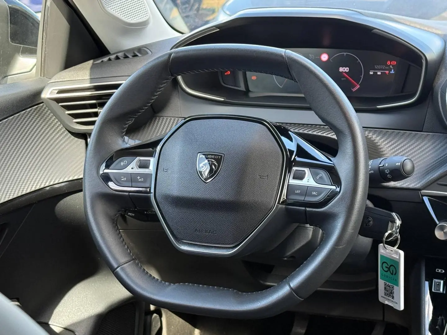 Vue rapprochée du volant Peugeot 208 1.2 100ch gris Artense, avec commandes intégrées et tableau de bord numérique.