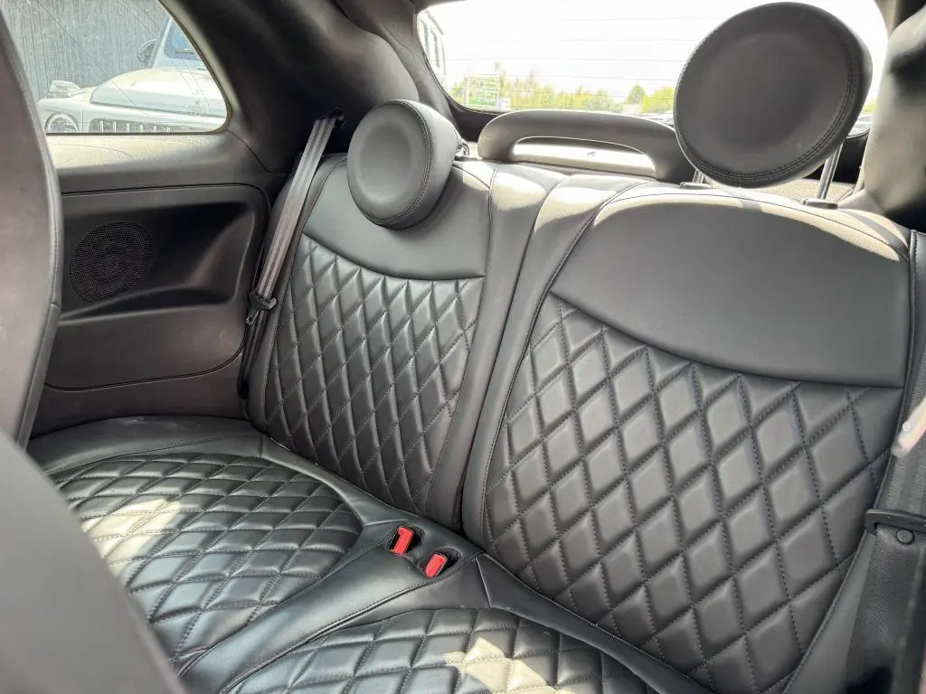 Vue rapprochée des sièges arrière en cuir noir matelassé de l'Abarth 500 blanc, avec appuie-têtes ronds.