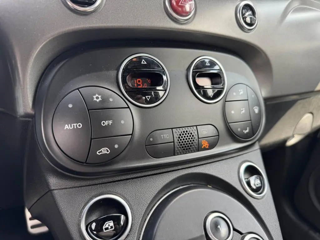 Vue rapprochée du tableau de bord noir de l'Abarth 500 blanc, montrant les commandes de climatisation et ventilation digitales.