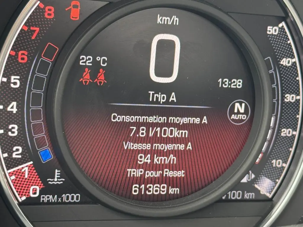 Gros plan sur le tableau de bord numérique de l'Abarth 500 blanc, affichant la vitesse, consommation et kilométrage.