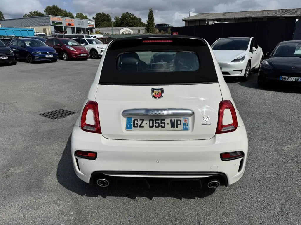 Vue arrière d'une ABARTH 500 blanche avec capote noire et double sortie d'échappement chromée sur parking.