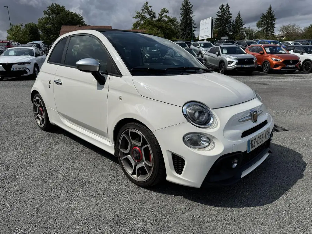 ABARTH 500 blanc en 3/4 avant droit avec jantes sport et coques de rétroviseurs chromées sur parking.