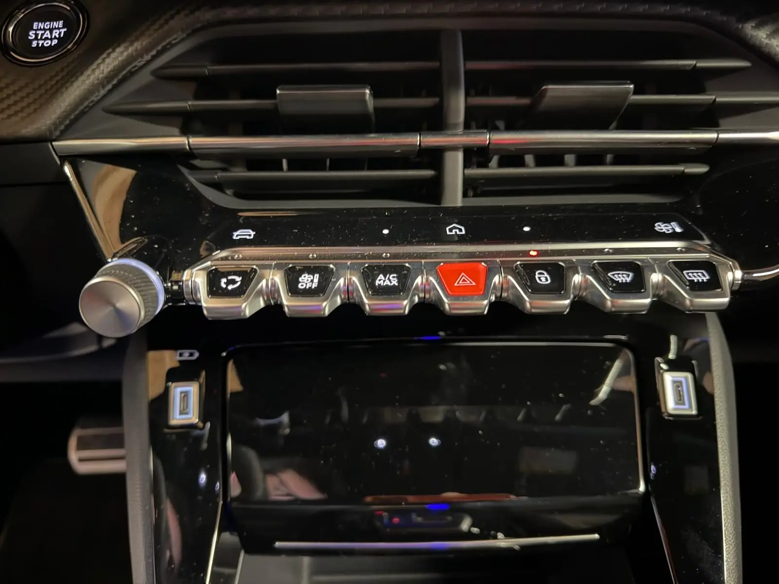Gros plan sur la console centrale noire du Peugeot 208 blanc, avec boutons de commande et bouton start/stop visible.