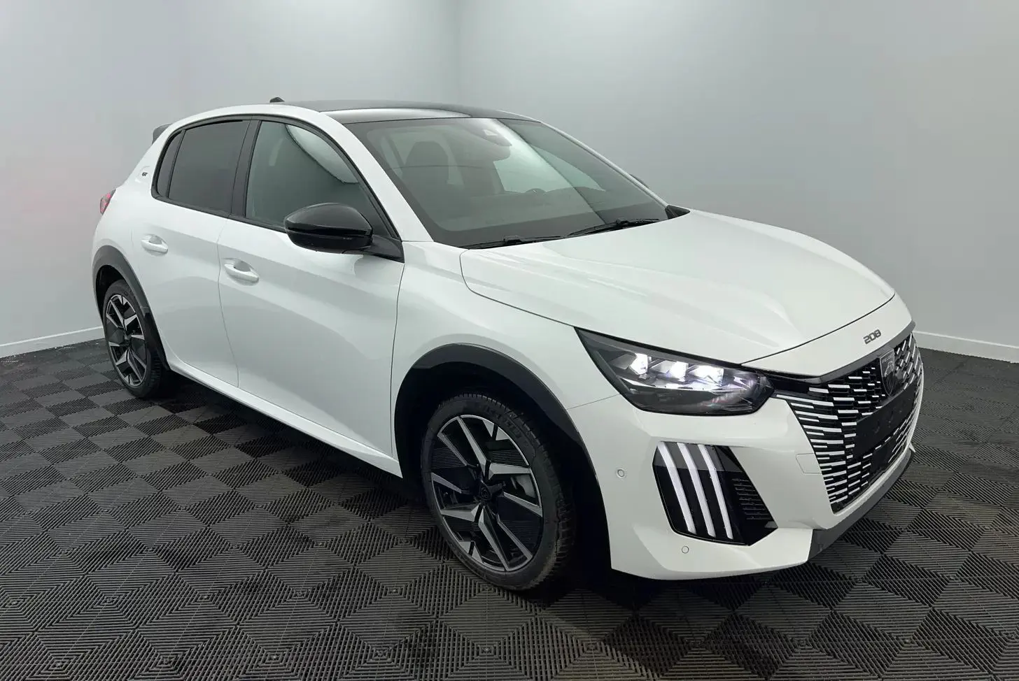 PEUGEOT 208 1.2 HYBRID 136 GT blanc en 3/4 avant droit, avec phares LED et jantes alliage noires.