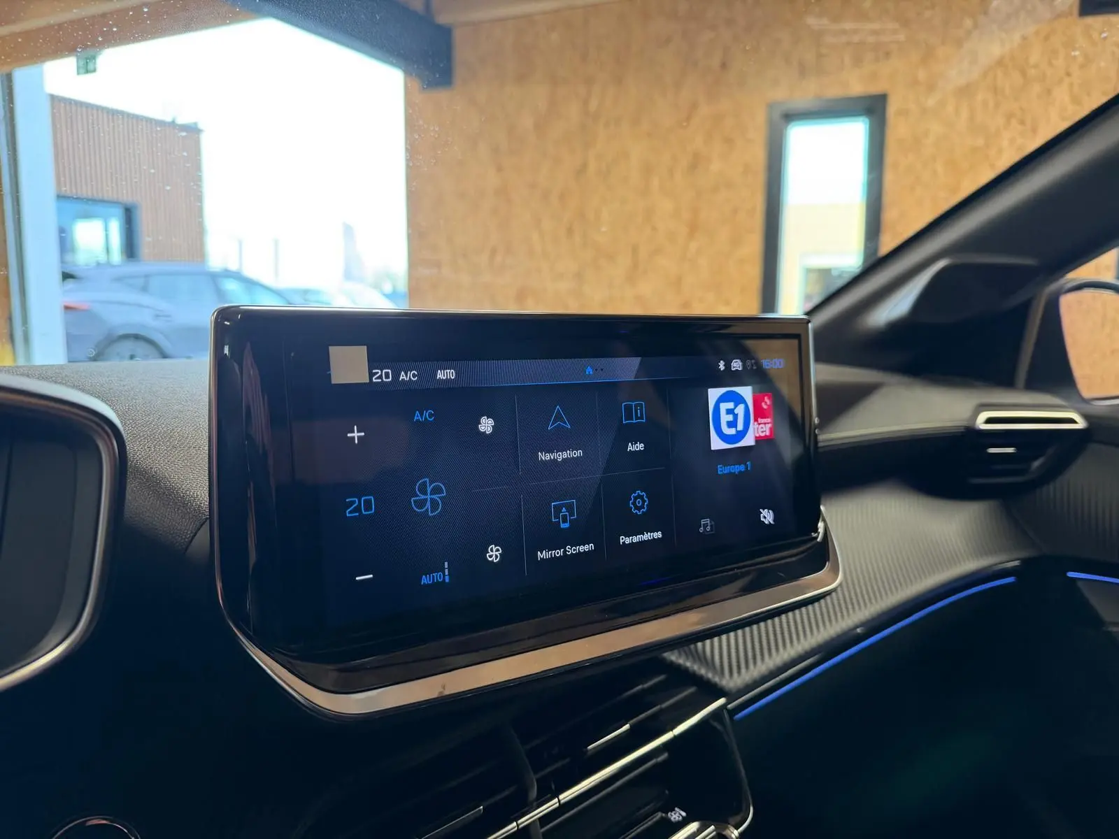 Écran tactile central du tableau de bord intérieur de la Peugeot 208 1.2 Hybrid 136 GT, ambiance noire avec éclairage bleu.