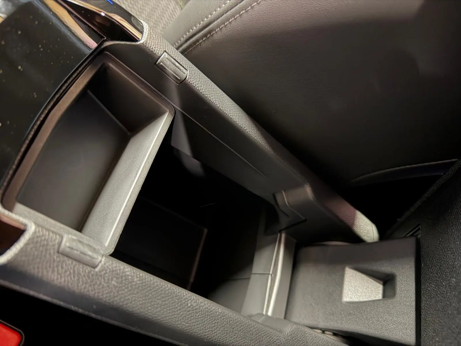 Gros plan sur le rangement central ouvert de l’intérieur noir en tissu du Peugeot 208 1.2 Hybrid 136 GT.