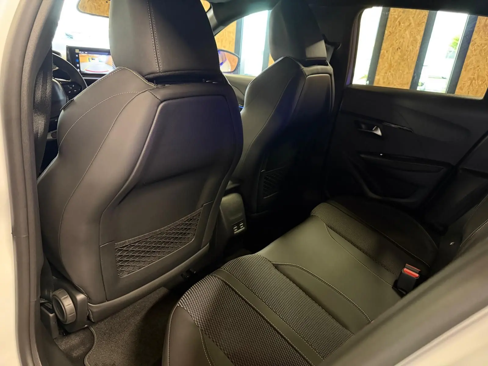Vue intérieure arrière côté droit du Peugeot 208 1.2 Hybrid 136 GT blanc, sièges noirs en tissu et cuir avec surpiqûres.