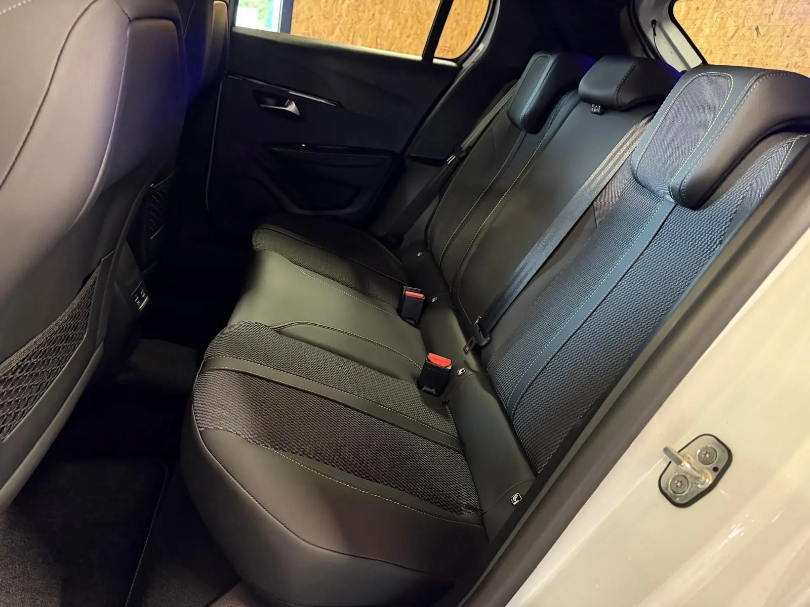 Vue intérieure côté droit des sièges arrière noirs en tissu et cuir de la Peugeot 208 1.2 HYBRID 136 GT blanche 2025.