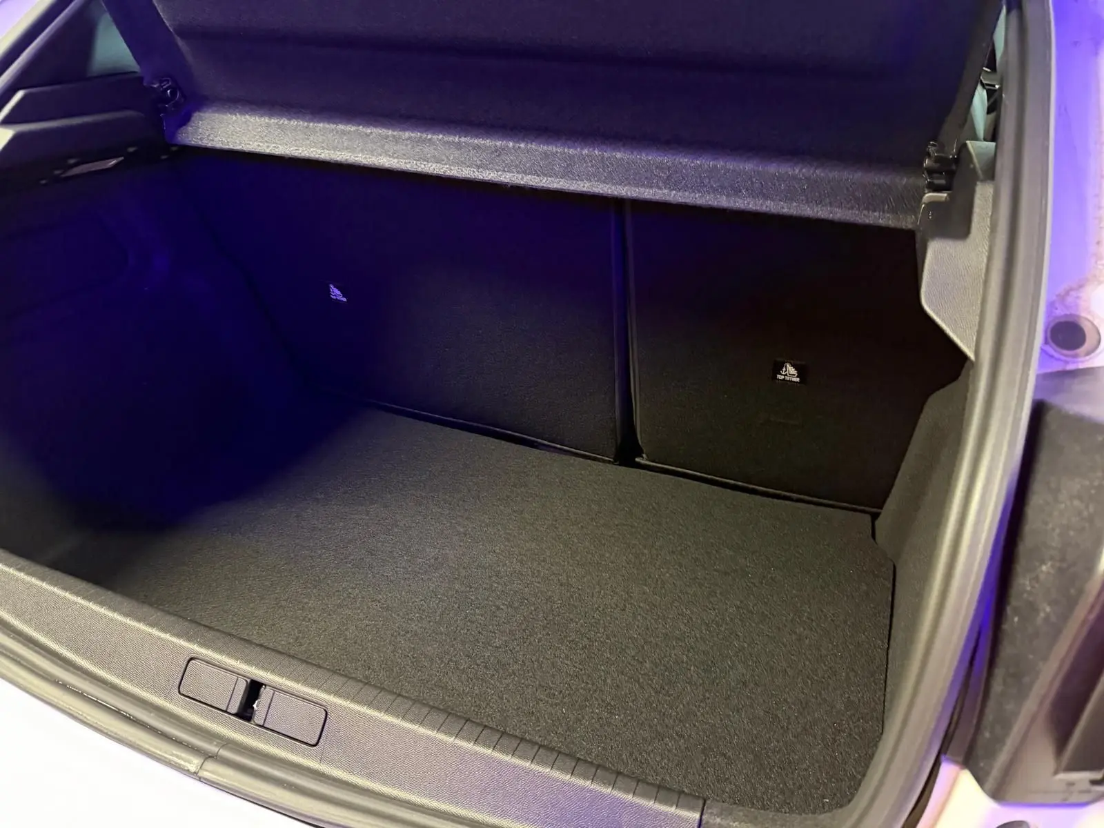 Coffre ouvert de la Peugeot 208 1.2 Hybrid 136 GT blanc, montrant un espace de rangement propre et vide.