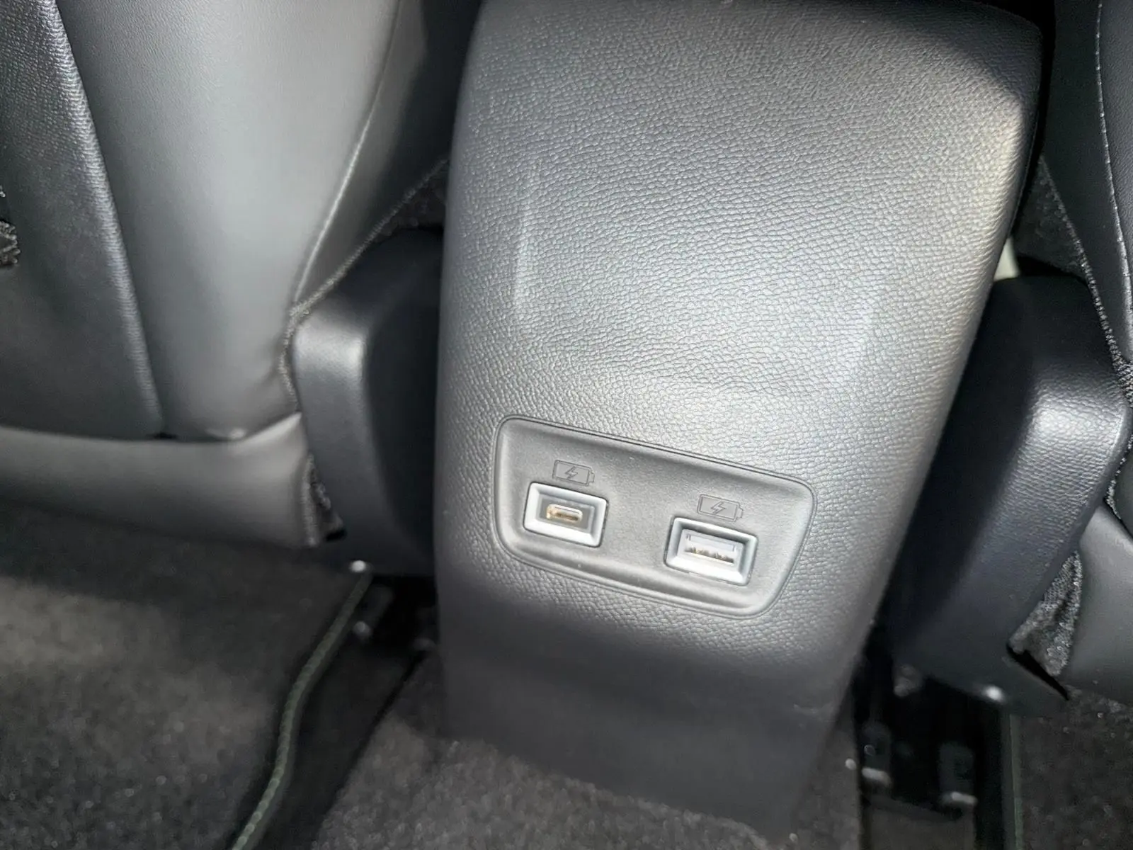 Prise USB double vue en gros plan sur la console centrale arrière d’une Peugeot 208 blanche hybride 2025.