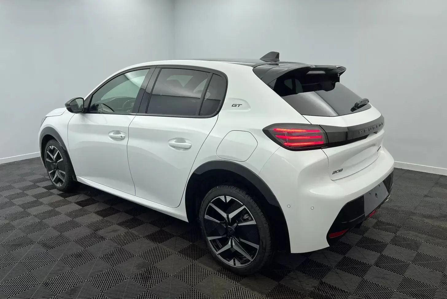Peugeot 208 1.2 Hybrid 136 GT blanc vue 3/4 arrière droit, avec jantes noires et toit contrasté noir.
