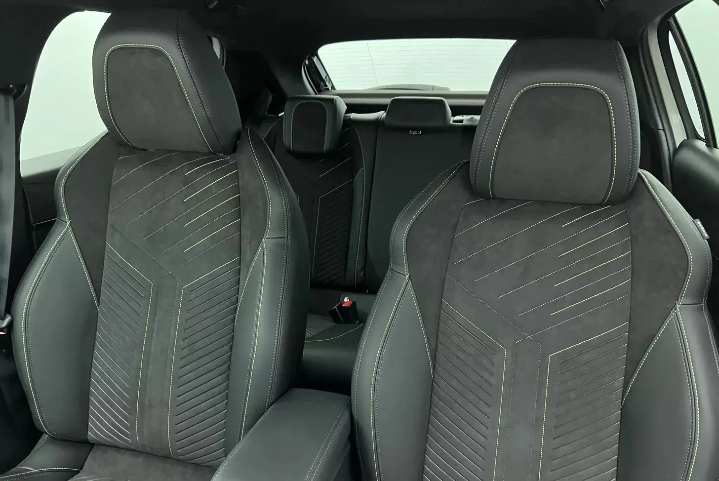 Gros plan sur les sièges avant noirs en tissu et alcantara avec surpiqûres jaunes dans l’habitacle d’une Peugeot 208 1.2 Hybrid 136 GT.