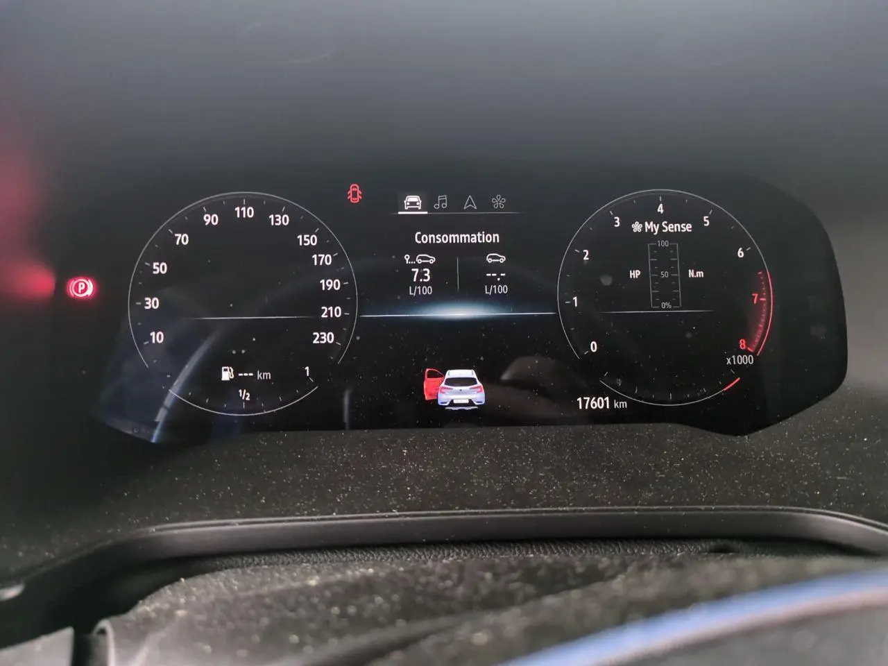 Tableau de bord numérique du Renault Captur blanc 2024 affichant consommation et alertes, vue frontale rapprochée.