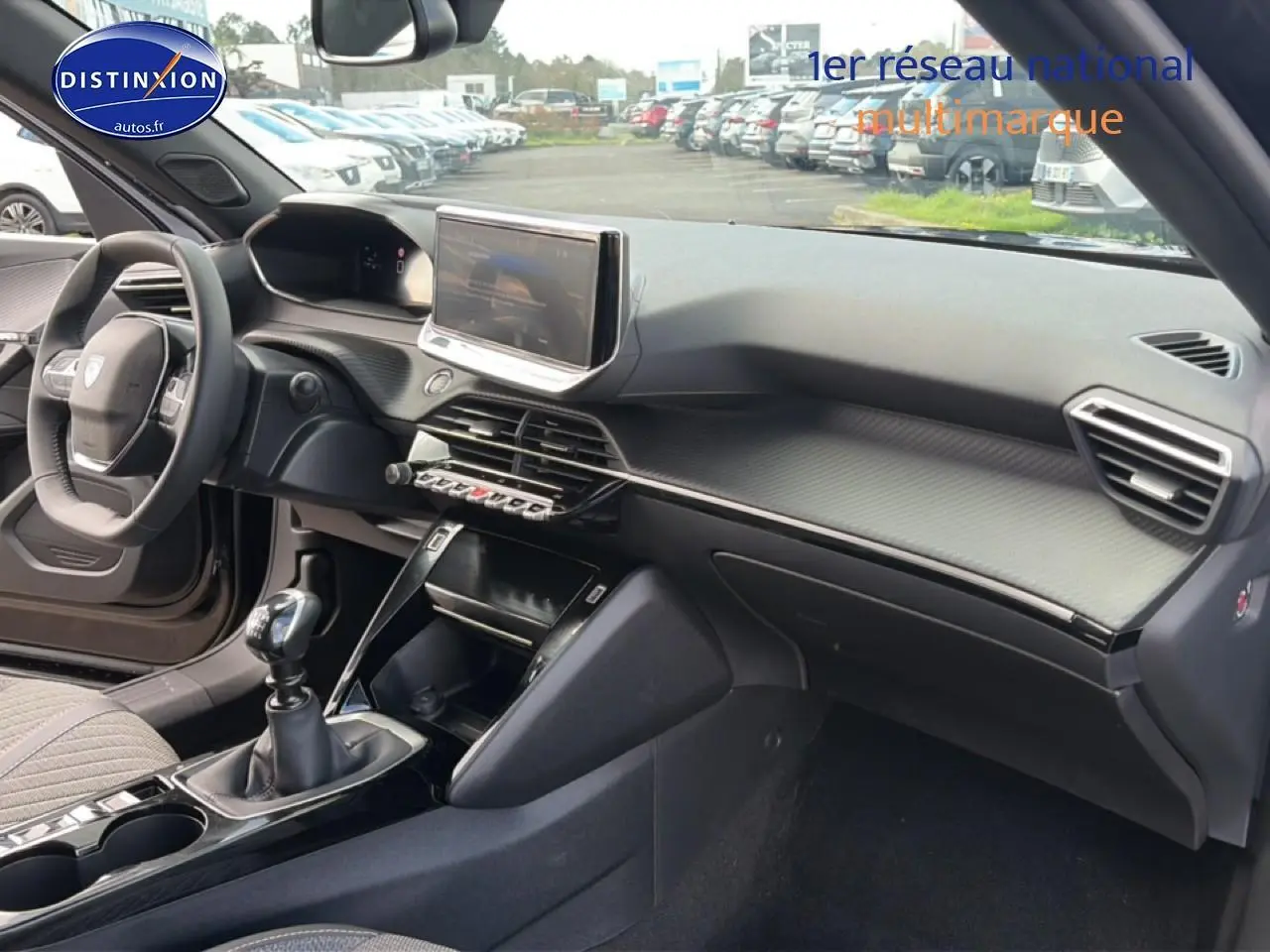 Vue intérieure côté passager du tableau de bord noir du Peugeot 2008 1.2 100 allure avec écran tactile et levier de vitesse manuel.