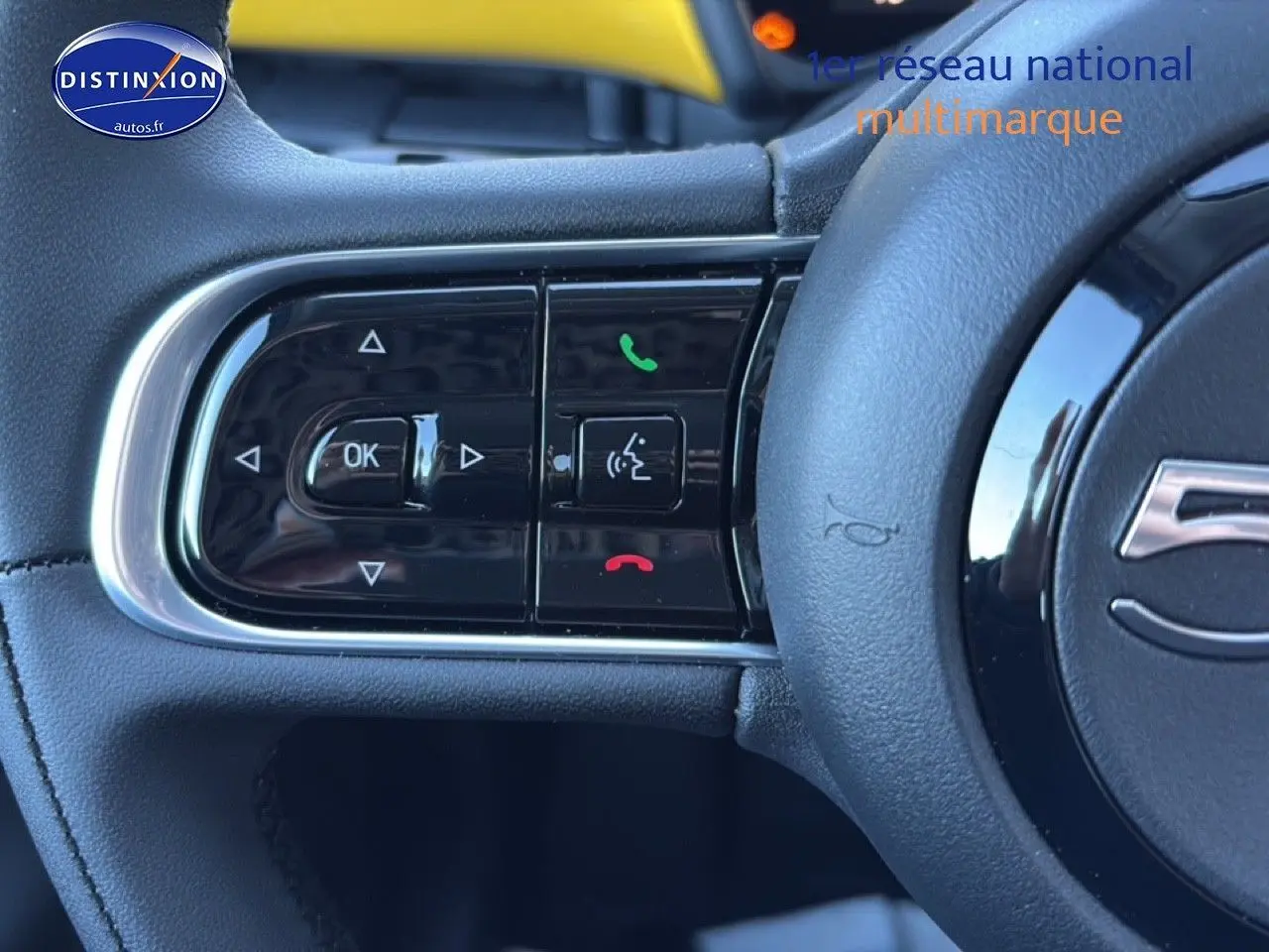 Gros plan sur les commandes au volant à gauche d'une FIAT 500 Yellow Gold Métal, avec boutons de téléphone et navigation.