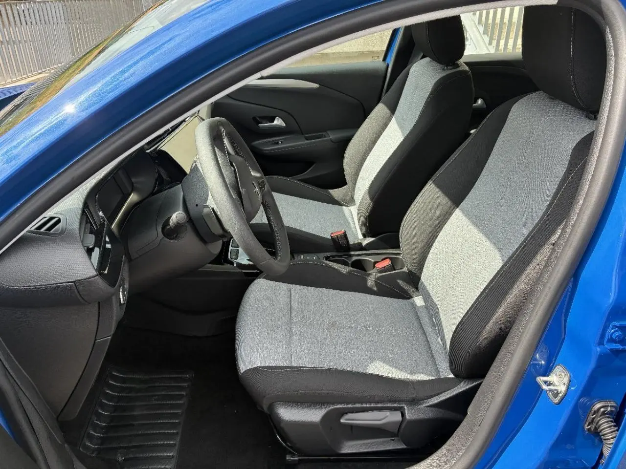 Vue intérieure côté conducteur de l’Opel Corsa 2025 bleu voltaik, montrant les sièges tissu bicolore et le volant.