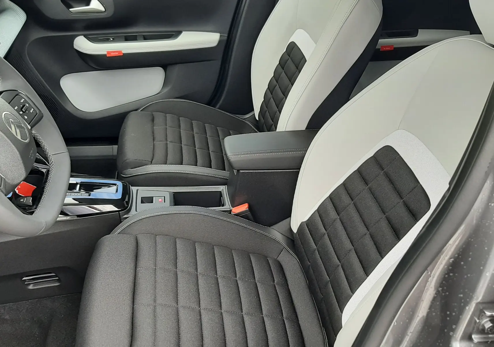 Vue intérieure côté conducteur de la Citroën C3 Aircross 2026, sièges bi-matière noir et blanc avec console centrale.