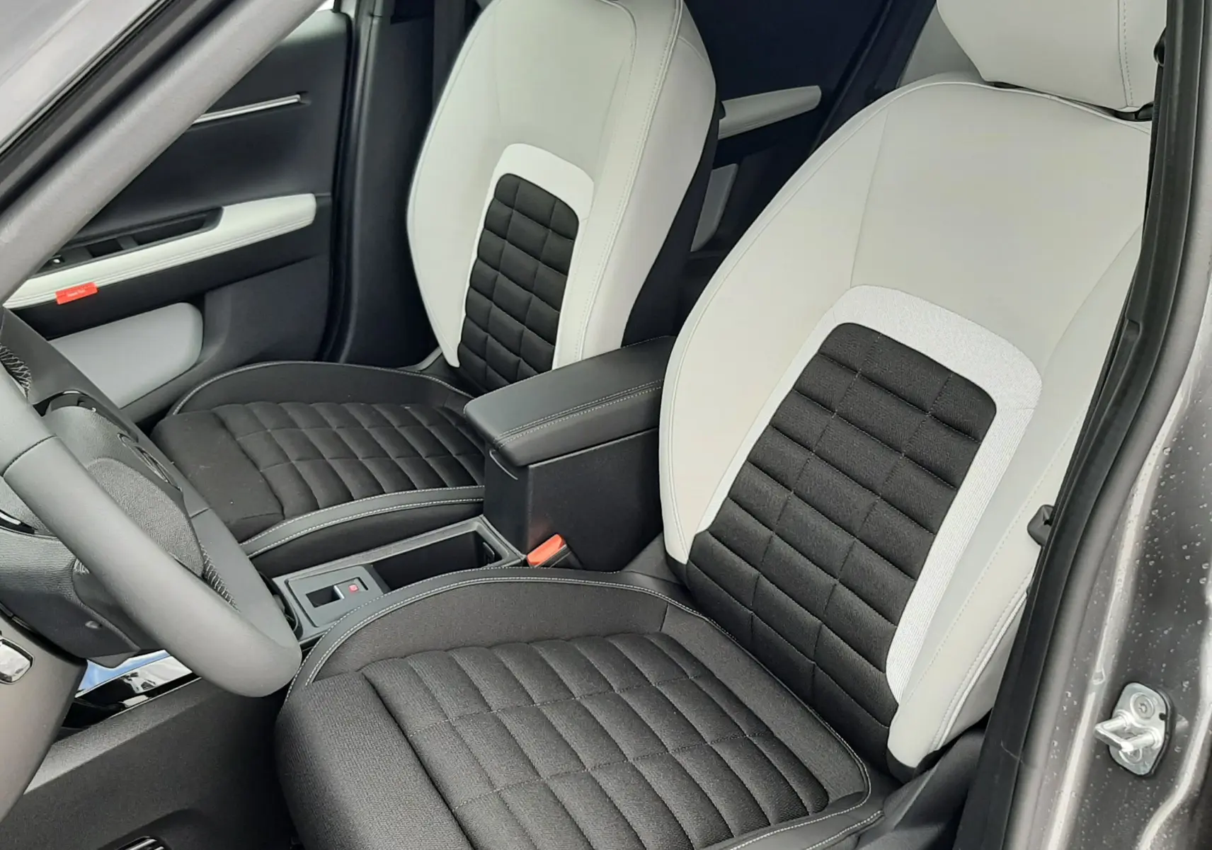 Vue intérieure côté conducteur du Citroën C3 Aircross 2026, sièges bi-matière noir et blanc avec surpiqûres grises.