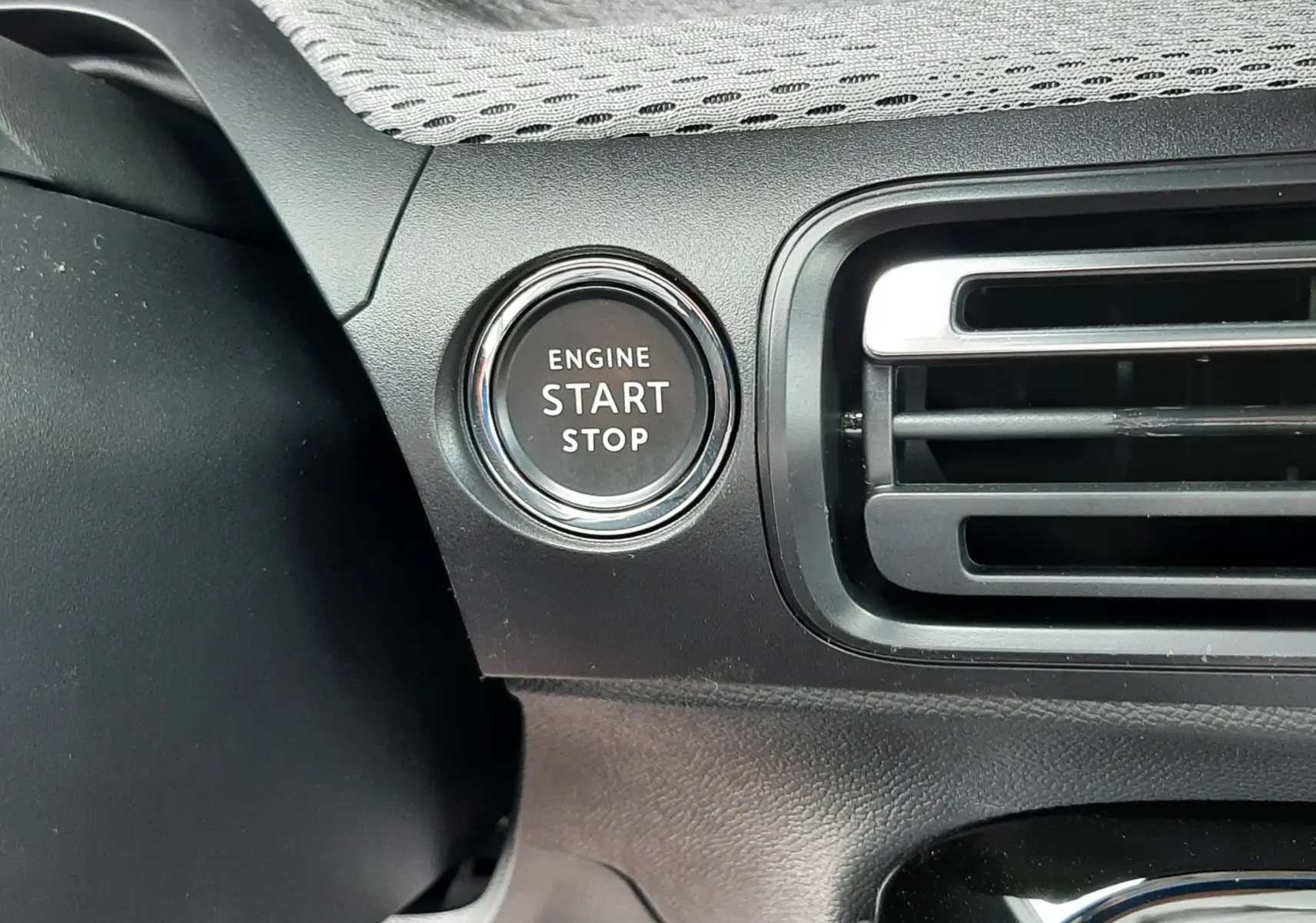 Gros plan sur le bouton start/stop moteur à gauche de la grille d’aération dans l’habitacle noir du Citroën C3 Aircross 2026.