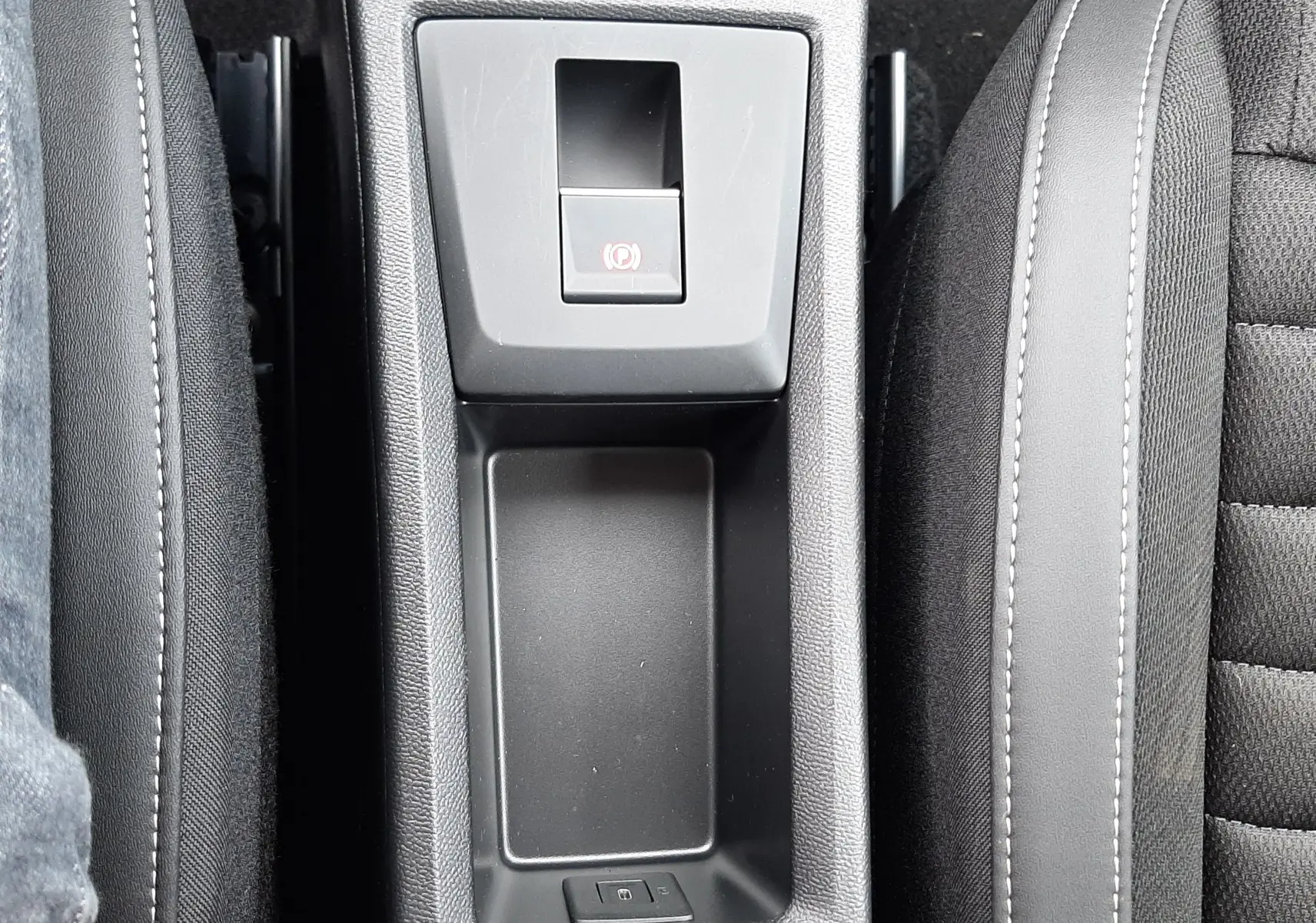 Vue plongeante sur la console centrale noire du Citroën C3 Aircross 1.2 Hybrid 145ch, avec frein à main électronique et accoudoirs.
