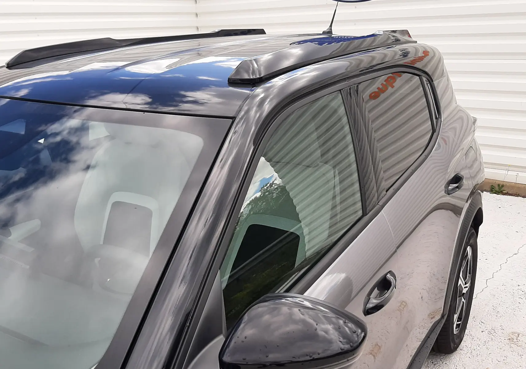 Vue 3/4 avant droit du Citroën C3 Aircross gris Mercury avec toit noir et barres de toit noires.