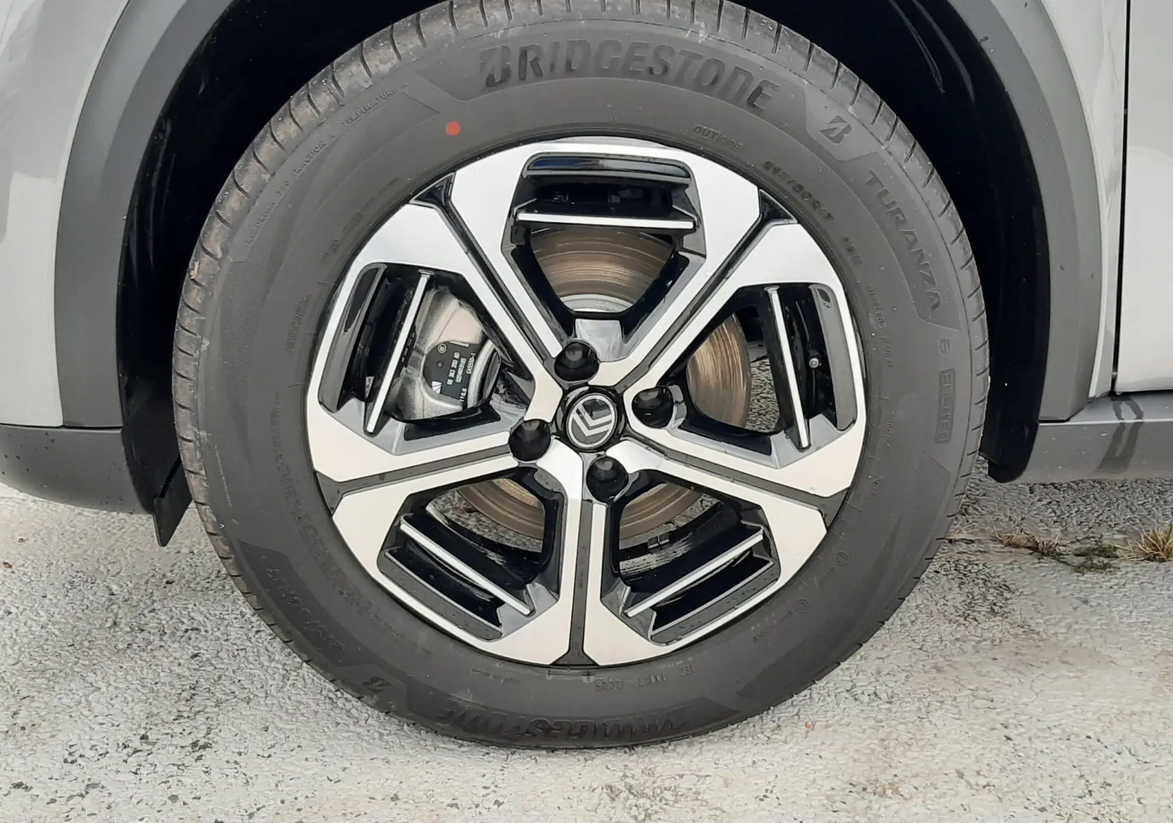 Gros plan sur la roue avant droite du Citroën C3 Aircross gris Mercury, jante alliage bicolore et pneu Bridgestone.