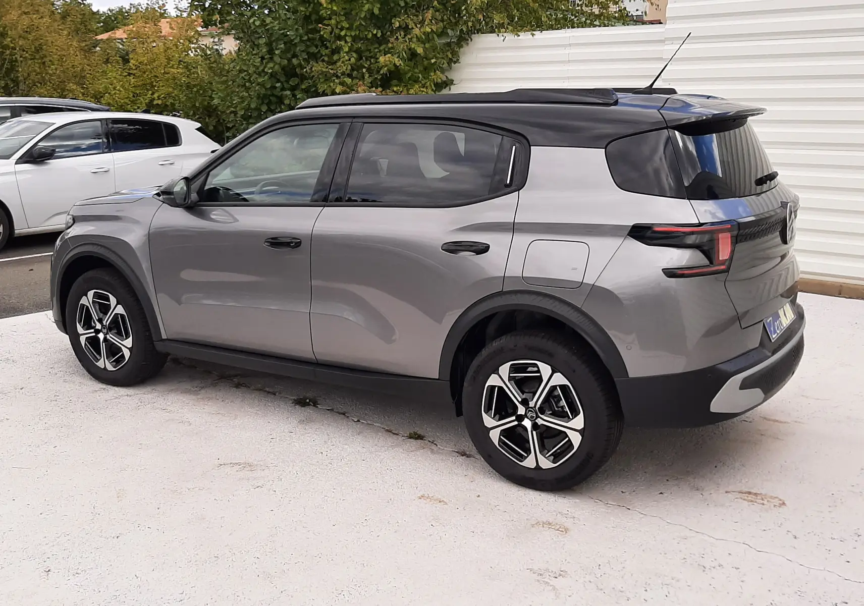 Citroën C3 Aircross 2026 gris Mercury avec toit noir, vue 3/4 arrière côté droit, jantes bi-ton et feux LED distinctifs.