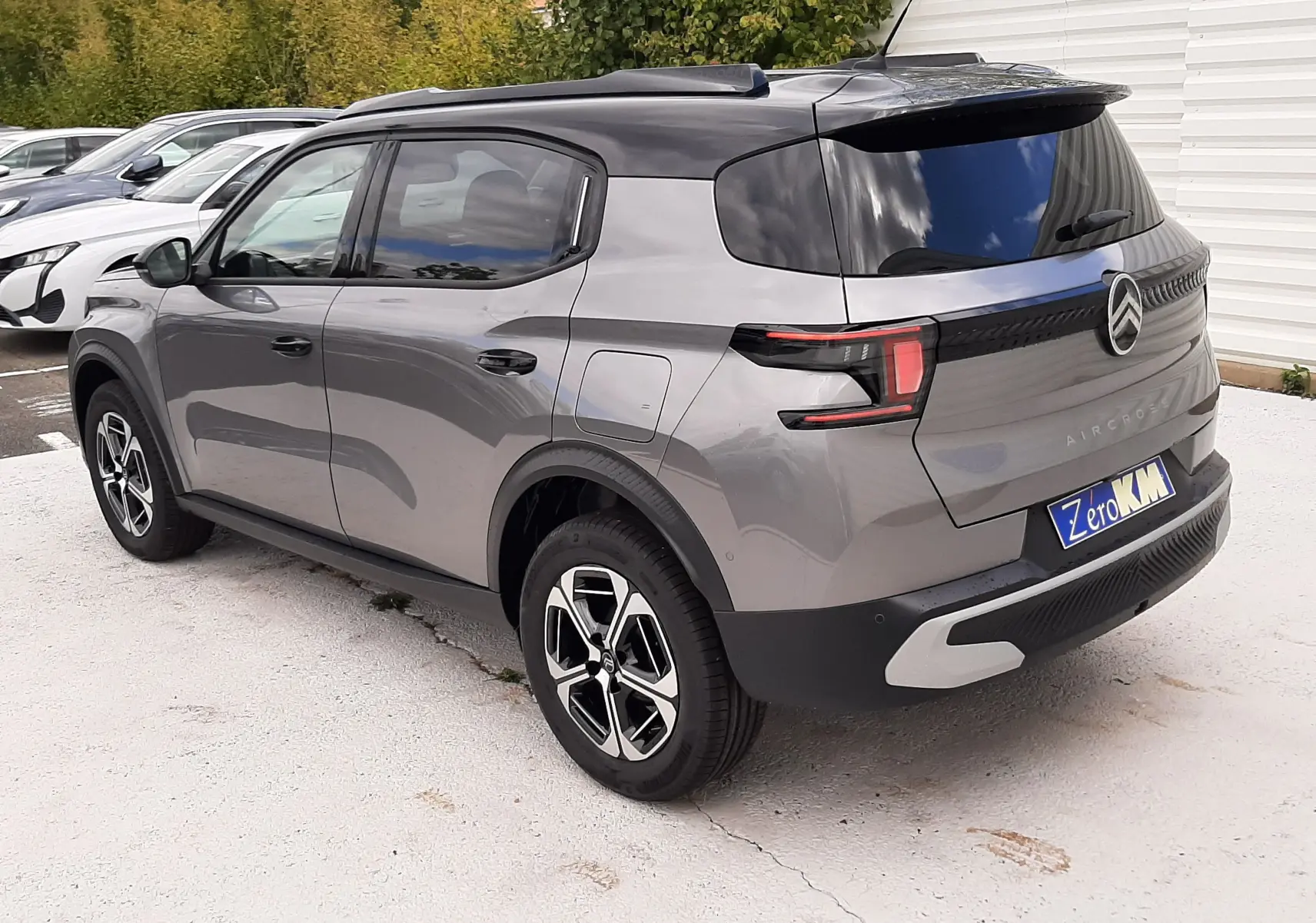 Vue 3/4 arrière droite d'un Citroën C3 Aircross gris Mercury avec toit noir et jantes bi-ton, stationné en extérieur.
