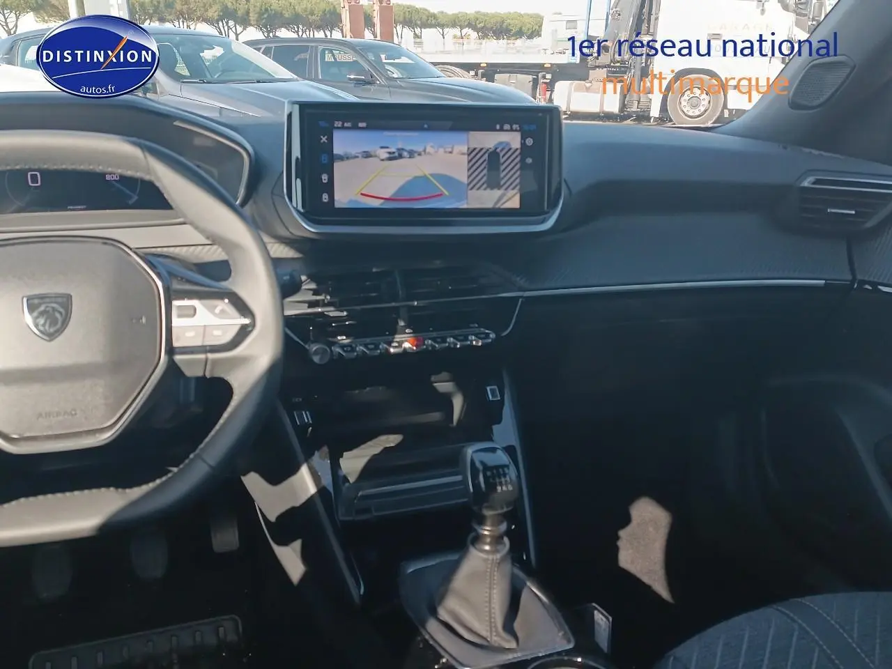 Intérieur de la Peugeot 2008 2025 en gris, vue du poste de conduite avec écran tactile et levier de vitesse manuel.