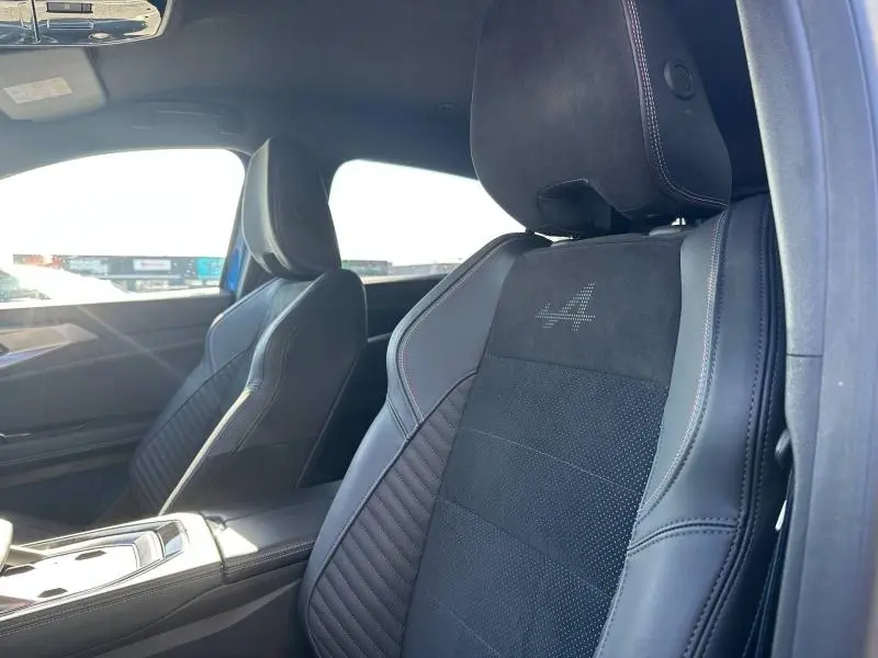 Vue rapprochée des sièges avant en cuir noir avec logo Alpine brodé sur le dossier, intérieur du Renault Rafale bleu.