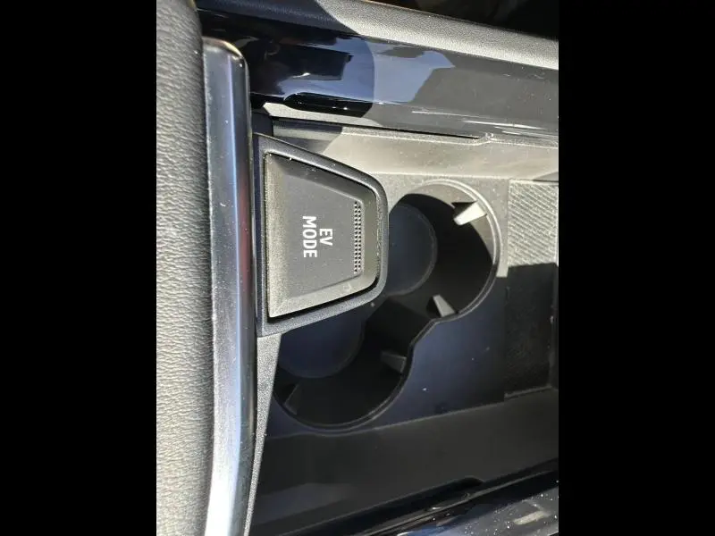 Vue rapprochée de la console centrale noire du Renault Rafale 1.2 E-Tech, bouton EV Mode et porte-gobelets visibles.