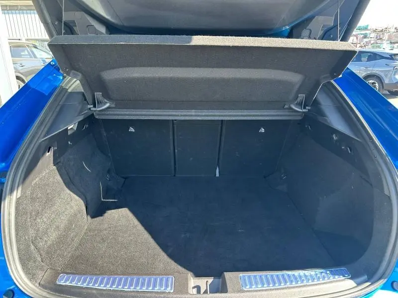 Coffre ouvert vu de l'arrière d'une Renault Rafale bleu sommet métallisé, espace de chargement vide et tapis noir.