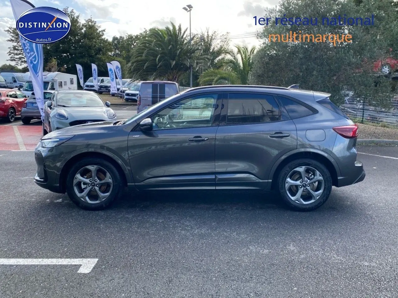 Ford Kuga 2025 gris Magnetic Fashion métallisé en vue de profil côté gauche sur parking extérieur.