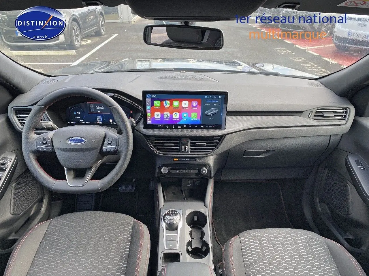 Vue intérieure avant du Ford Kuga 2025 avec tableau de bord moderne, écran tactile central et volant multifonction.