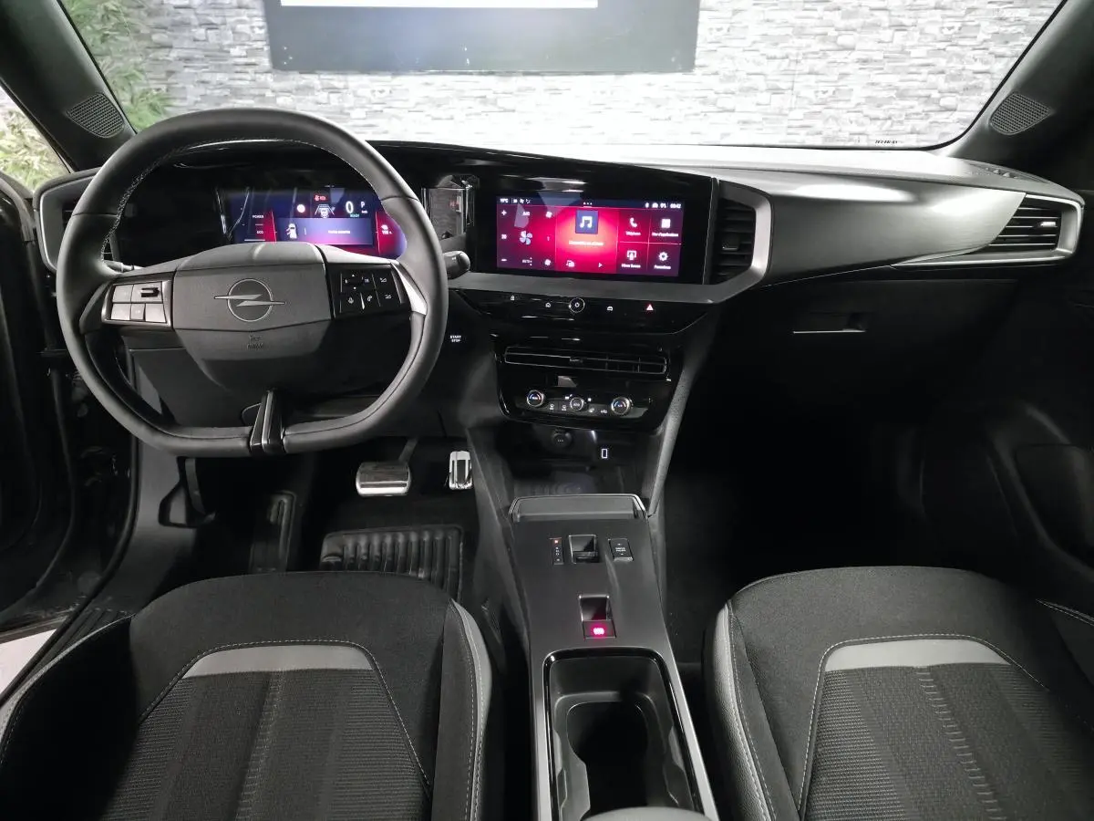 Vue intérieure avant de l’Opel Mokka-e 2025 noire, tableau de bord digital et écran tactile central lumineux.