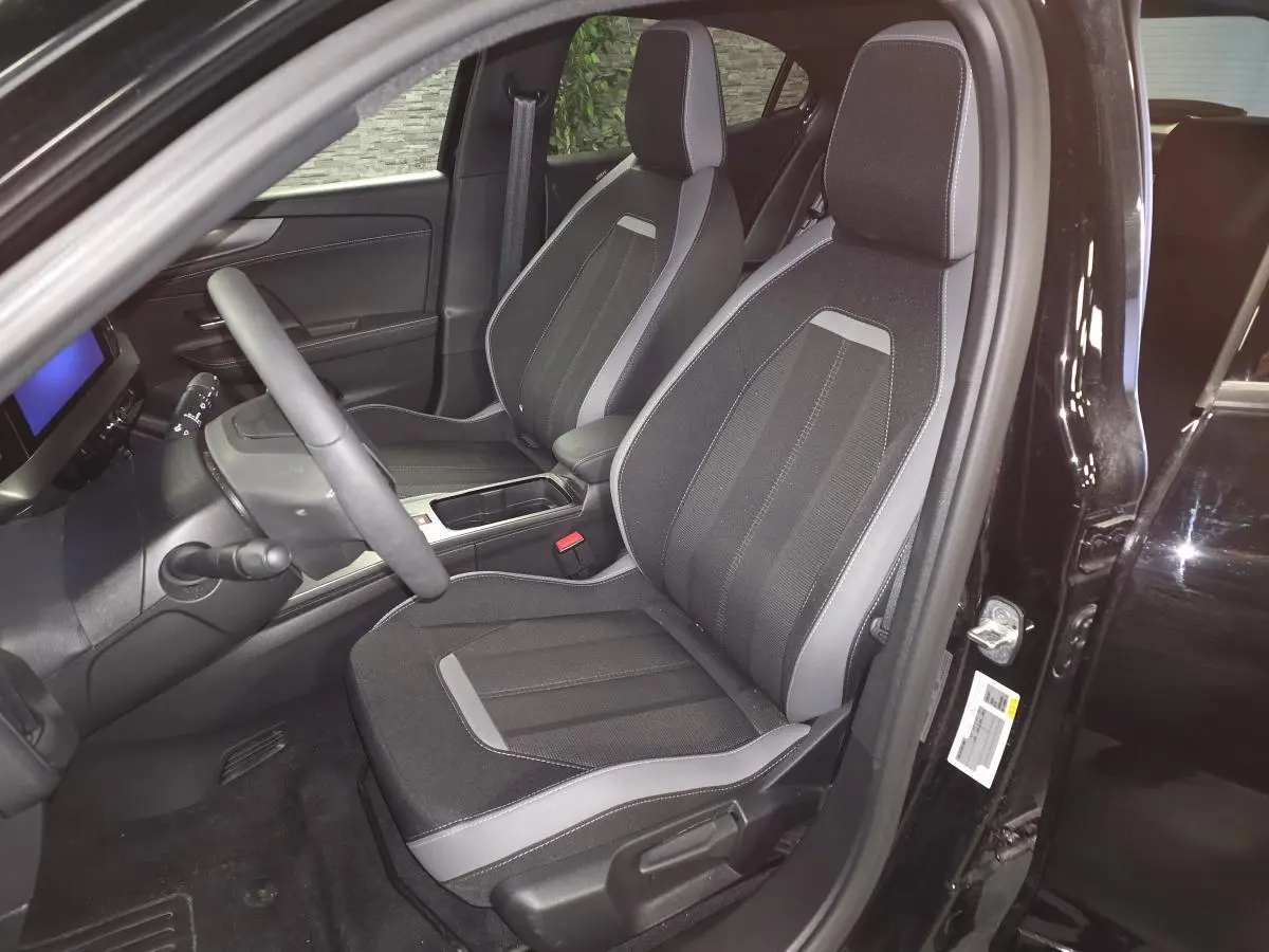 Intérieur avant droit de l'Opel Mokka-e noir 2025, sièges tissu noir et gris avec console centrale visible.