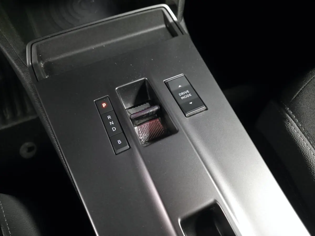 Gros plan sur la console centrale noire de l’Opel Mokka-e 2025, avec sélecteur de boîte automatique et bouton Drive Mode.